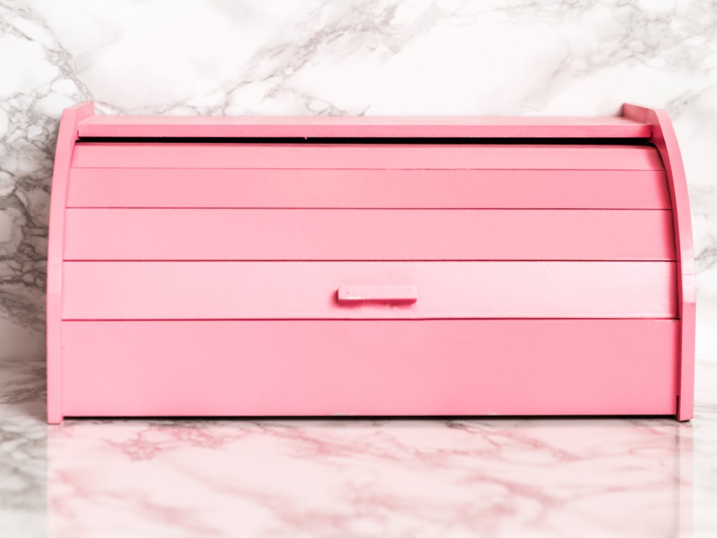 Pink wooden bread box on white marble background