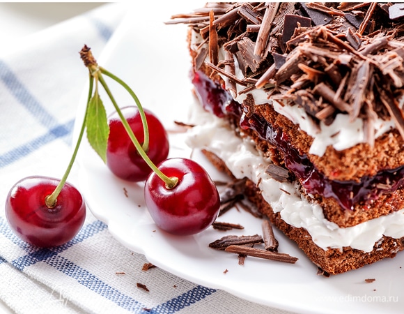 Black Forest cake piece on white plate with cherries berries clo