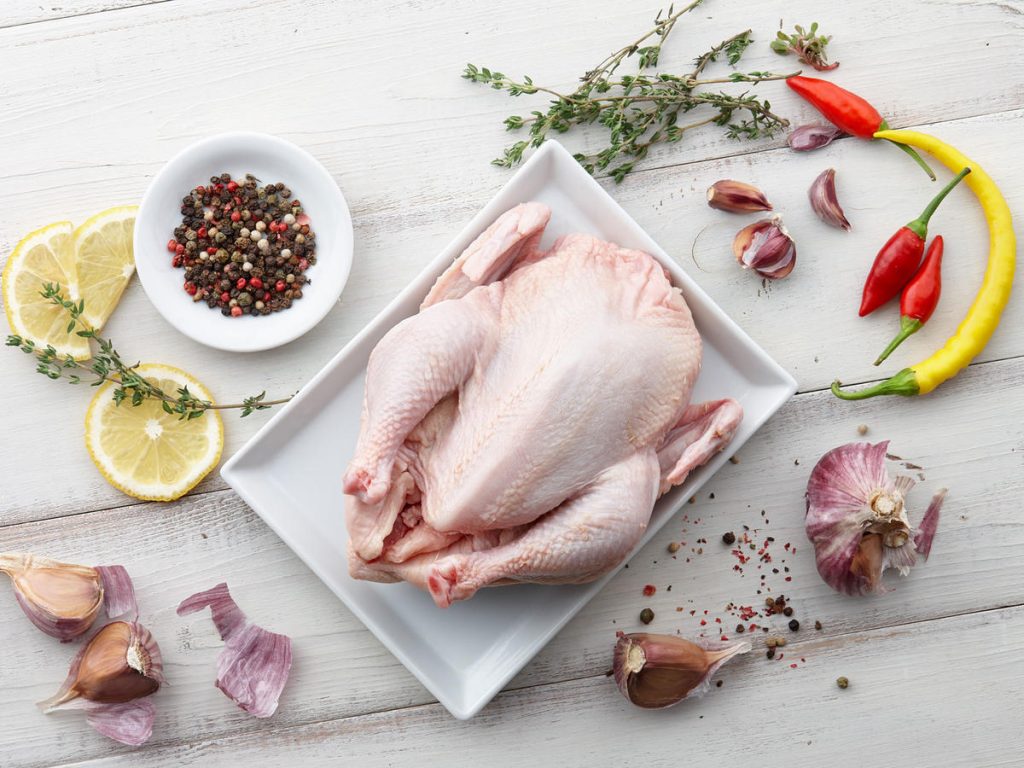 Cooking raw chicken with herbs and spices on white wooden background, top view